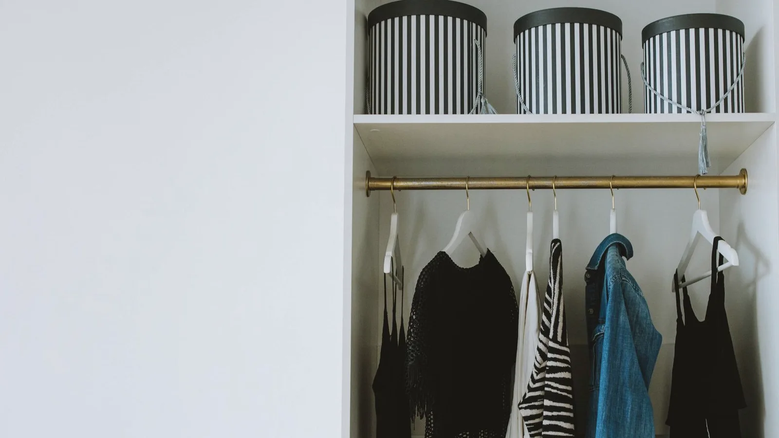 Storage boxes stacked on a shelf above a closet rail of hanging clothes
