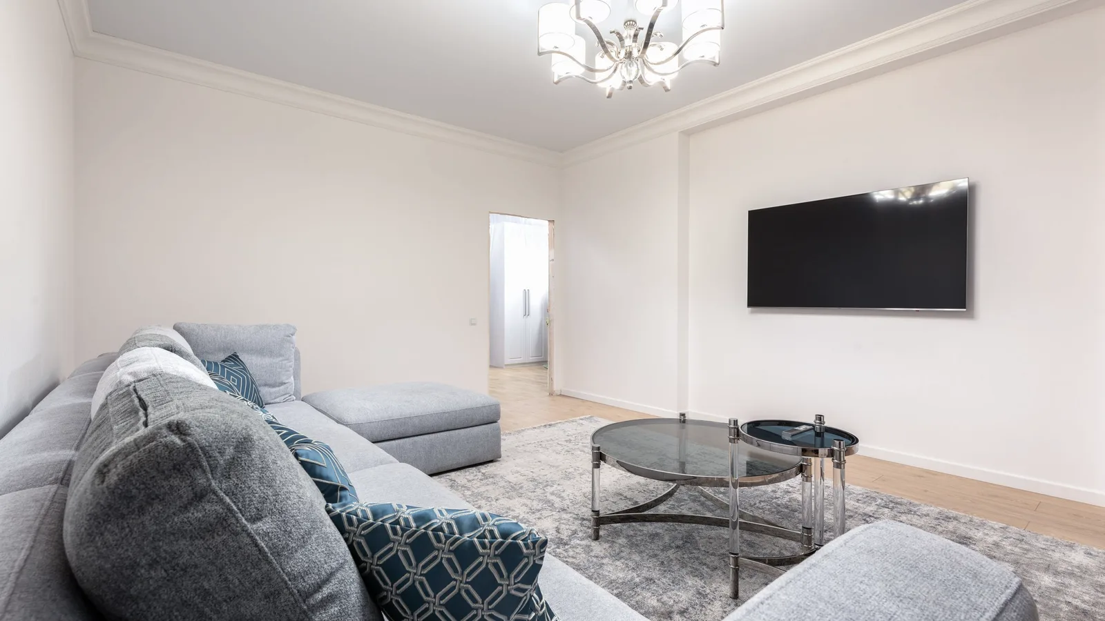 A living room with a sofa, shelves, plants and framed pictures